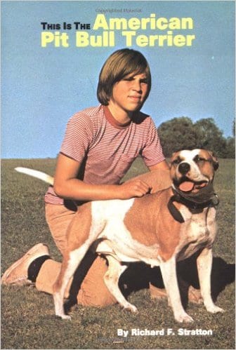 A young man sitting on the ground with his dog.