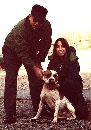 A man and woman petting a dog on the street.