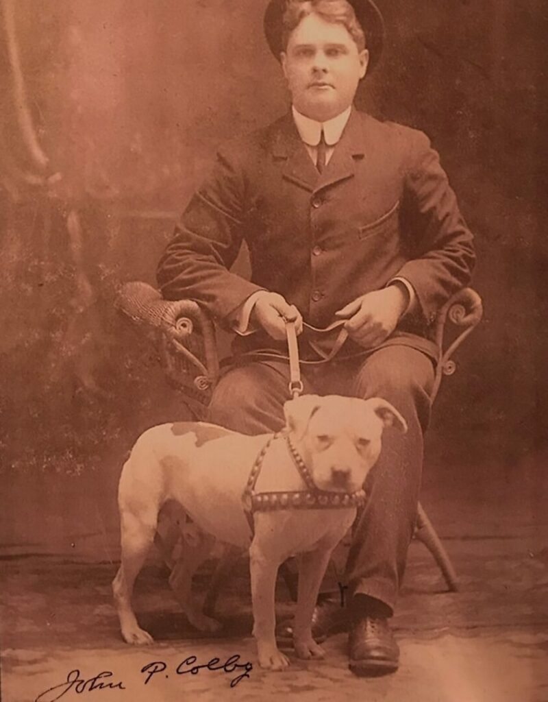 A man sitting in an old chair with his dog.