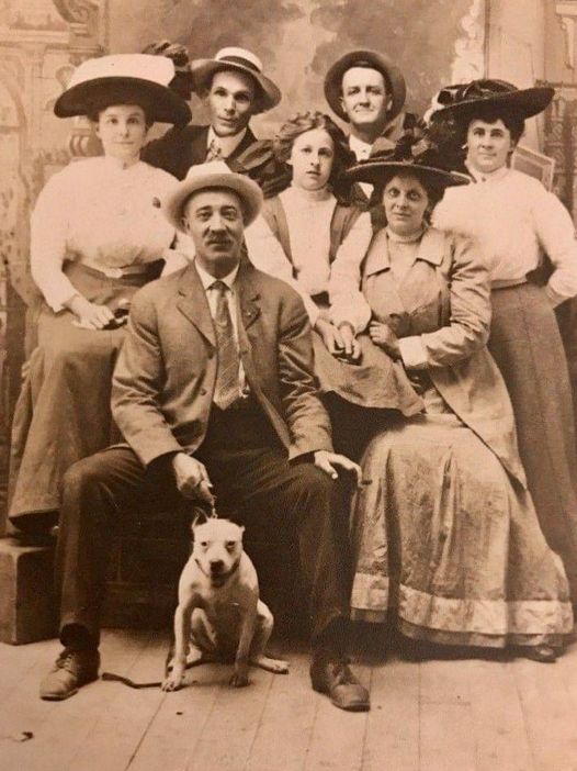 A group of people with hats and one man sitting in front.